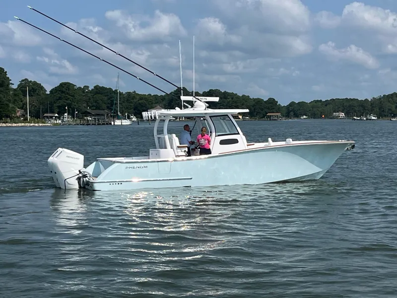 Slide: The Image of A 2026 Phenom 34 boat on calm water with two people on board. - 2