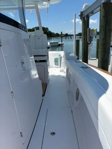 Slide: The Image of A sleek, modern boat with a white deck and seating area, docked at a tranquil pier. - 19