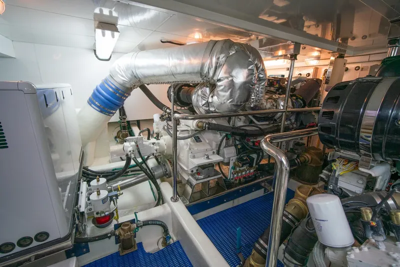 Slide: The Image of The engine room of a 2013 Ocean Alexander 65 Pilothouse features complex piping and engines. - 50