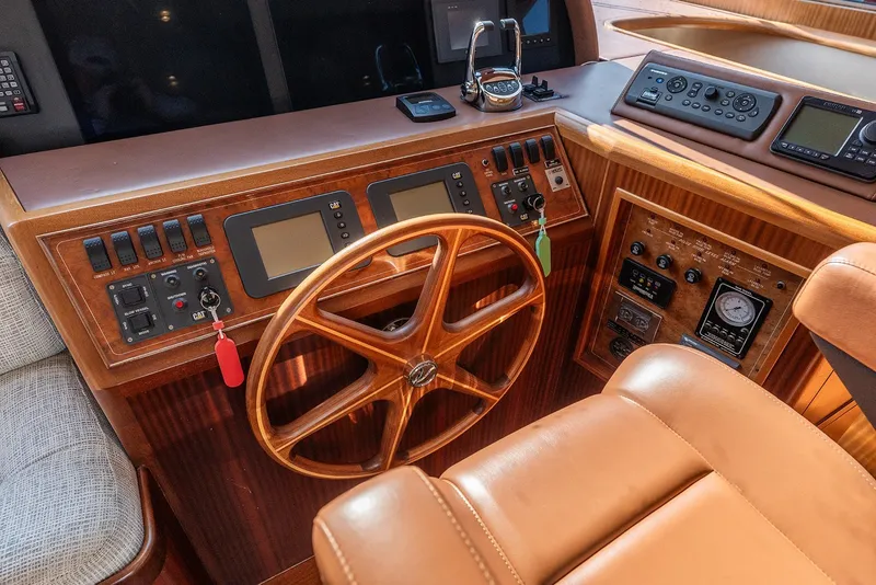 Slide: The Image of Pilothouse interior of 2013 Ocean Alexander 65, featuring wooden steering wheel and control panels. - 19