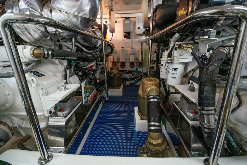 Slide: The Image of The engine room of a 2013 Ocean Alexander 65 Pilothouse features complex engines and piping. - 54