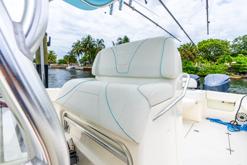 Slide: The Image of 2020 SeaVee 340Z boat interior with white seating, docked near lush greenery. - 42