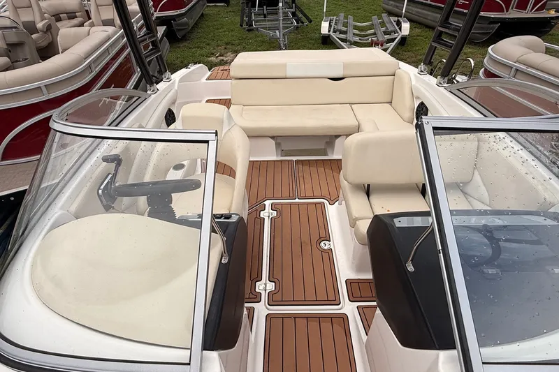 Slide: The Image of 2018 Regal 1900 ES Bowrider with beige seating and wooden deck, parked among other boats. - 4