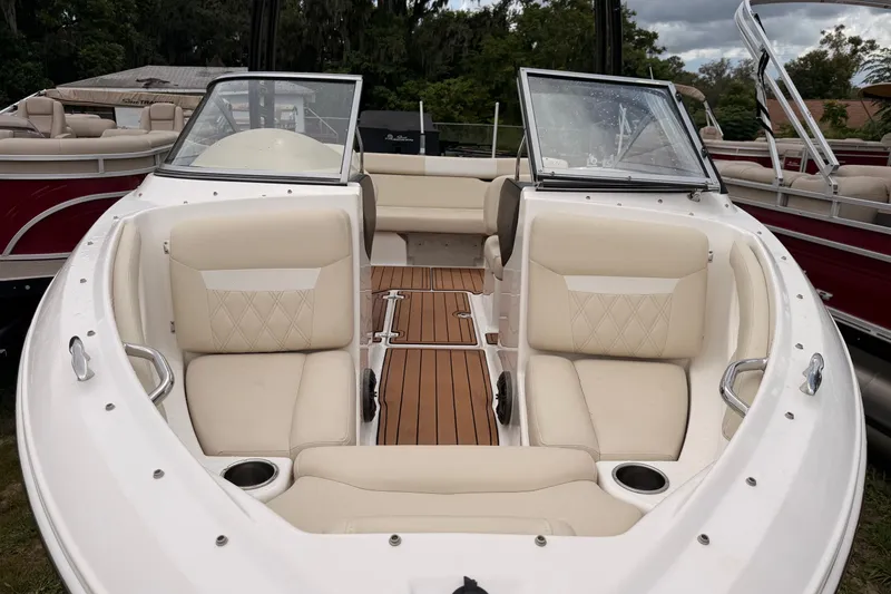 Slide: The Image of 2018 Regal 1900 ES Bowrider with beige seating and wooden deck, parked outdoors. - 1
