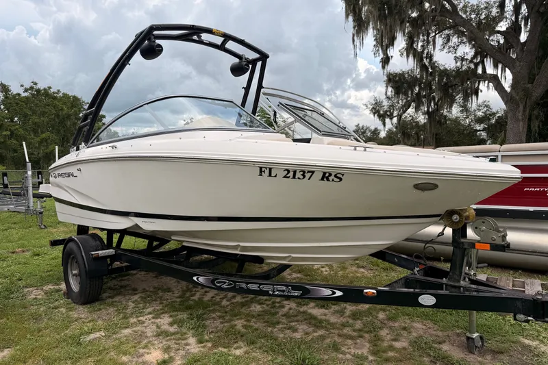 The Image of 2018 Regal 1900 ES Bowrider on trailer, parked outdoors with trees in background. - 0