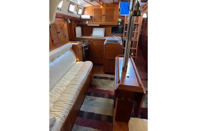 Slide: The Image of 1987 Tayana Vancouver 42 yacht interior with wood finish, white seating, and kitchen area. - 23