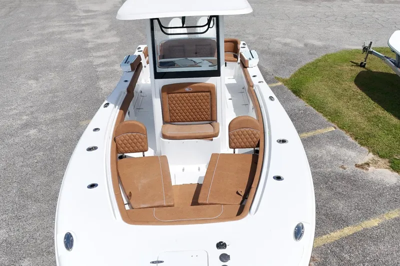 Slide: The Image of 2027 Sea Hunt Ultra 265SE boat with tan seating and white deck, parked on pavement. - 14