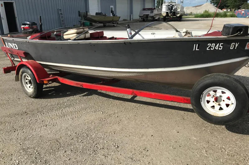 Slide: The Image of 1989 Lund 16 Pike SS boat on red trailer, parked outdoors. - 18