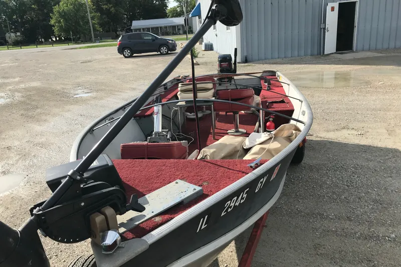 Slide: The Image of 1989 Lund 16 Pike SS fishing boat with red interior, parked outdoors. - 21