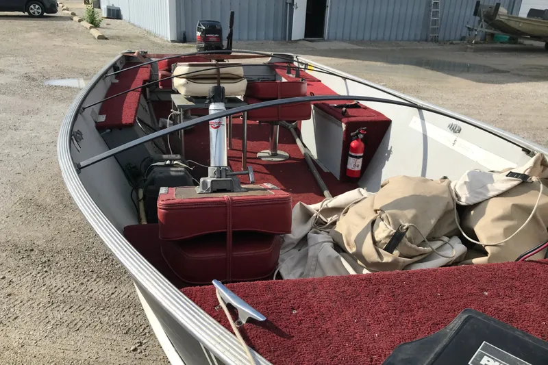 Slide: The Image of 1989 Lund 16 Pike SS boat with red interior, docked outdoors. - 16