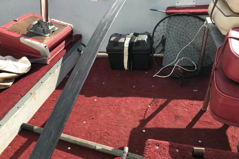 Slide: The Image of Interior of a 1989 Lund 16 Pike SS boat with red seating and fishing gear. - 24