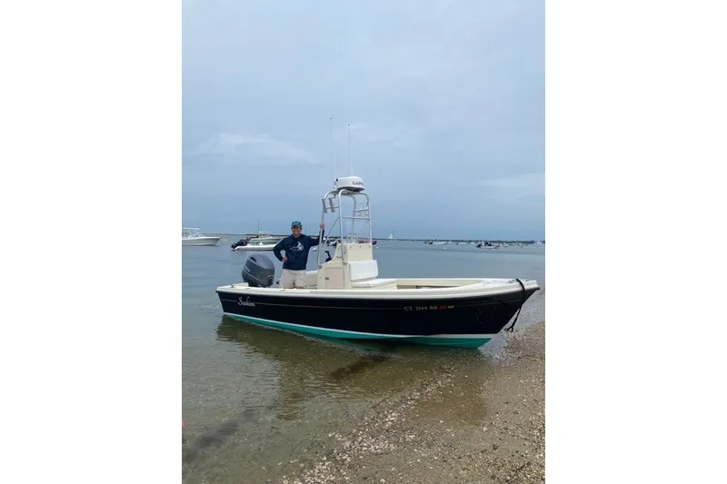 Slide: The Image of 2001 Parker 1801 Center Console boat on a beach with a person standing beside it. - 1