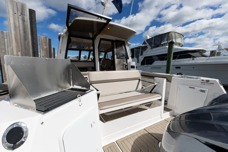 Slide: The Image of Manufacturer Provided Image: 2025 Cutwater C-288 Coupe boat with outdoor seating and grill, docked under a blue sky. - 16