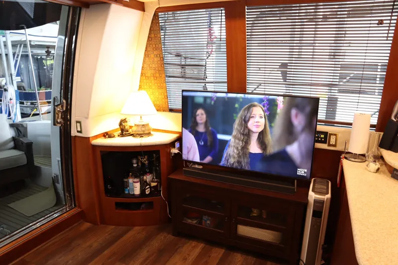 Slide: The Image of Interior of 1999 Carver Yacht Voyager 530 with TV, lamp, and wooden decor. - 12