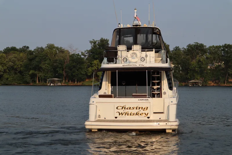Slide: The Image of 1999 Carver Yacht Voyager 530 named "Chasing Whiskey" cruising on a serene lake. - 4