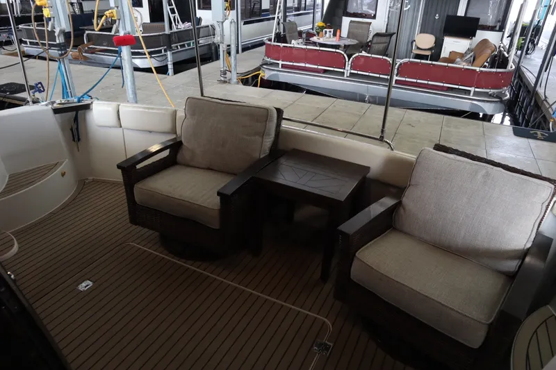 Slide: The Image of 1999 Carver Yacht Voyager 530 deck with cushioned chairs and table in marina setting. - 30