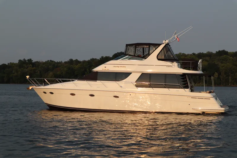 Slide: The Image of 1999 Carver Yacht Voyager 530 cruising on a serene lake at sunset. - 2