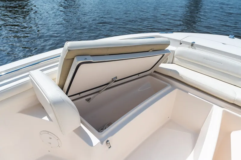 Slide: The Image of 2018 Grady-White Fisherman 216 boat with open storage compartment, white seating, and water backdrop. - 30