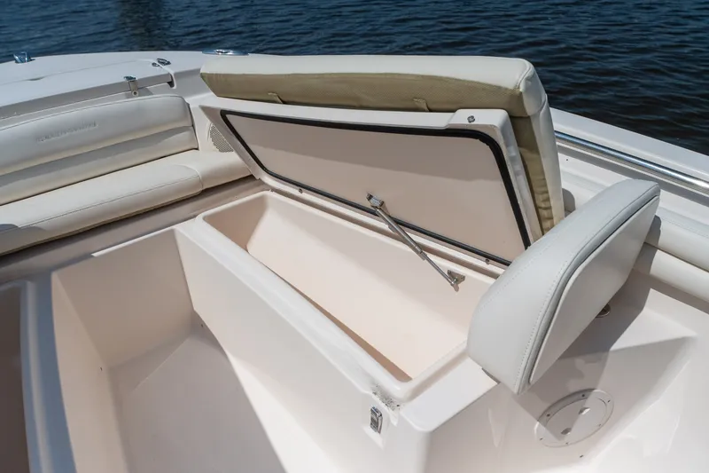 Slide: The Image of 2018 Grady-White Fisherman 216 boat with open storage compartment, white seating, and water backdrop. - 31