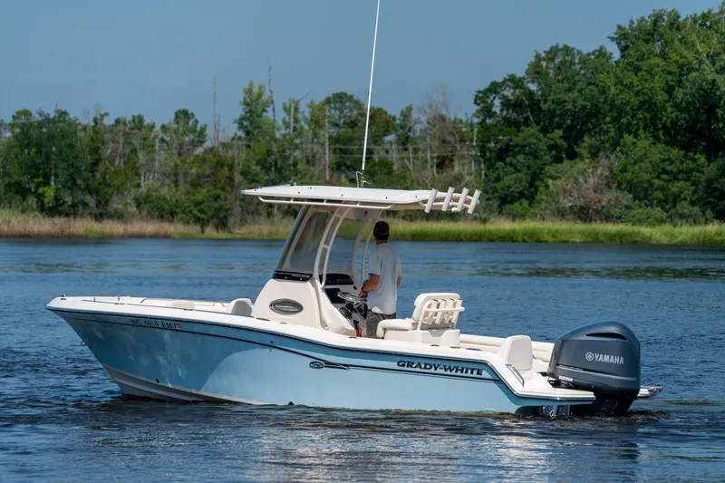Slide: The Image of 2018 Grady-White Fisherman 216 boat cruising on a serene lake with lush greenery. - 6