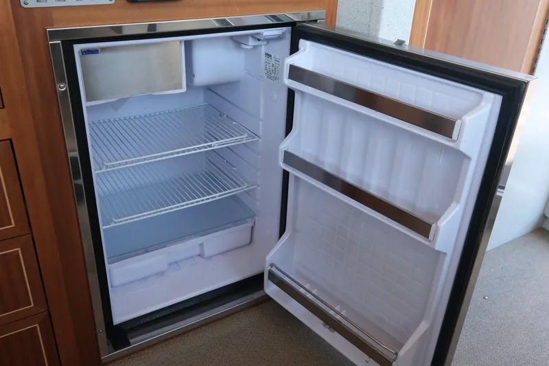 Slide: The Image of Open refrigerator inside a 2022 KingFisher 3425 GFX Offshore boat, showing empty shelves. - 18