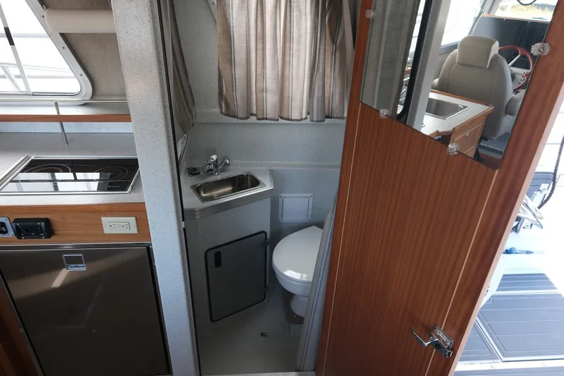 Slide: The Image of Interior of 2022 KingFisher 3425 GFX Offshore boat, featuring compact bathroom and kitchenette. - 16