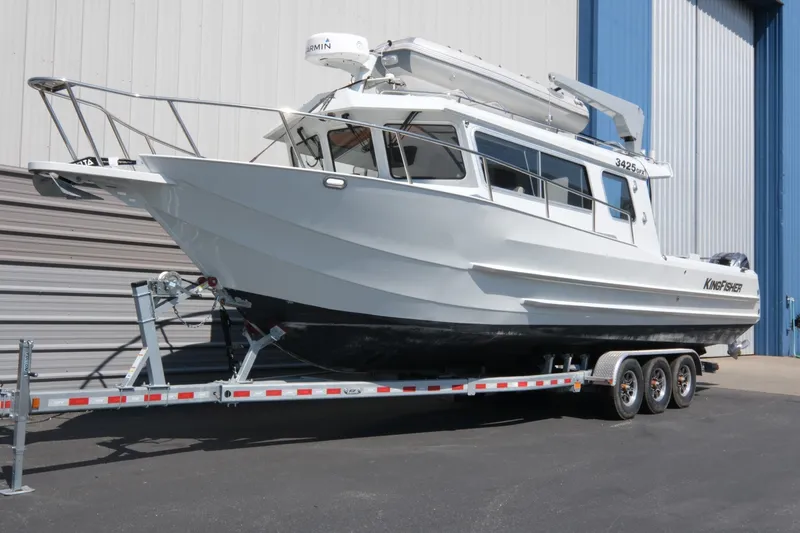 The Image of 2022 KingFisher 3425 GFX Offshore boat on trailer, parked outside a blue and white building. - 1