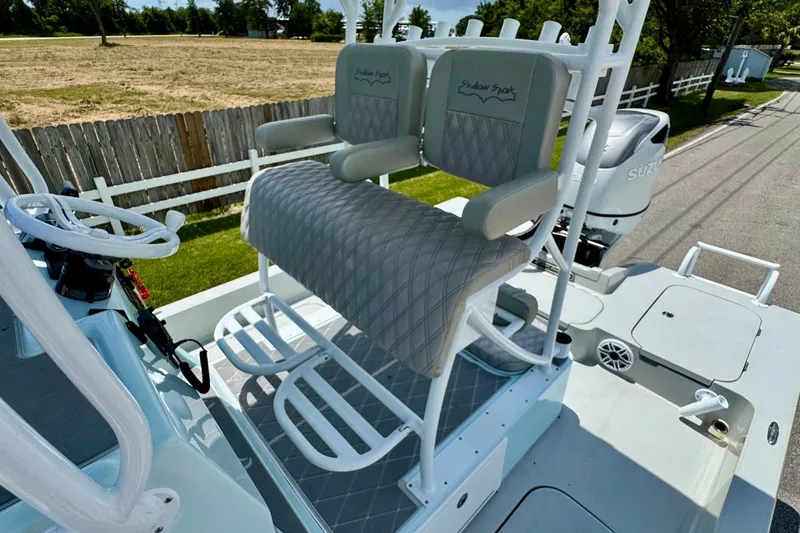Slide: The Image of 2024 Shallow Sport 25 X3 boat with dual seats and steering wheel, parked outdoors. - 9