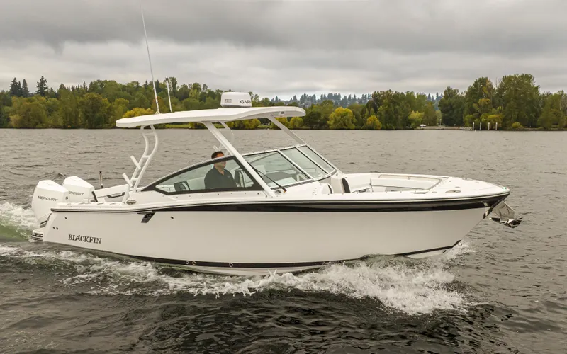 Slide: The Image of 2024 Blackfin 272 DC boat cruising on a lake with lush green trees in the background. - 43