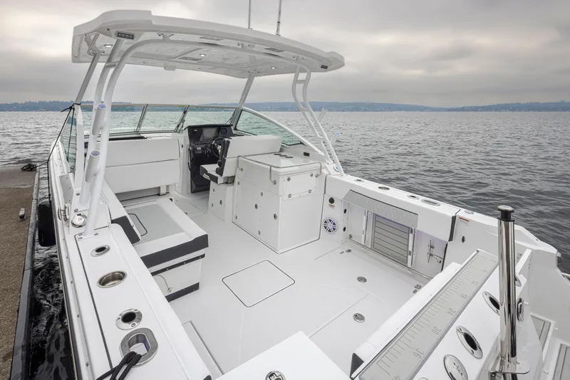 Slide: The Image of 2024 Blackfin 272 DC boat interior with seating and storage, docked by the water. - 9
