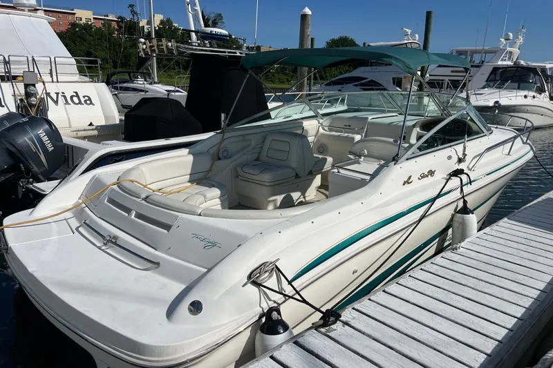 The Image of 1998 Sea Ray 280 Sun Sport boat docked at marina, featuring sleek white design and green accents. - 0