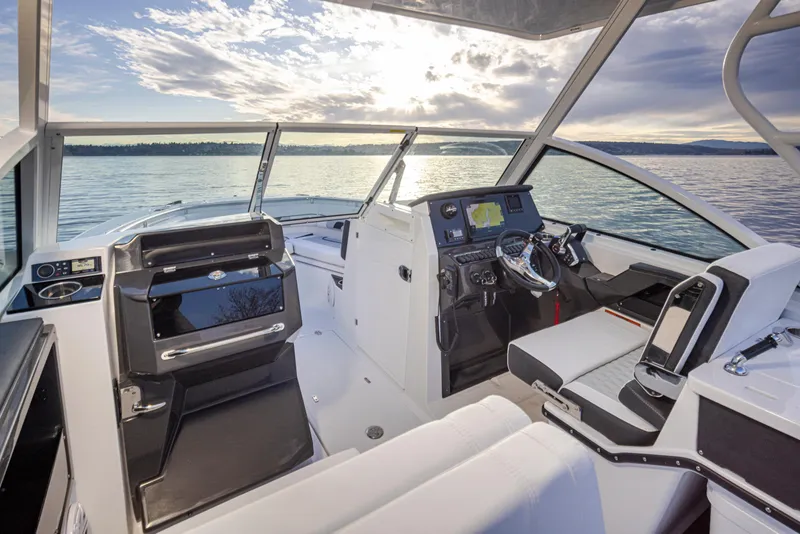 Slide: The Image of 2024 Blackfin 252 DC boat interior with modern dashboard and seating, on a serene lake. - 23