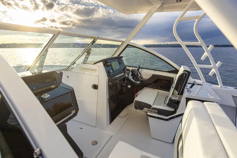 Slide: The Image of 2024 Blackfin 252 DC boat interior with helm and seating, on a serene water backdrop. - 8
