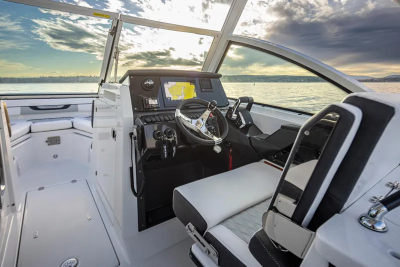 Slide: The Image of 2024 Blackfin 252 DC boat interior with modern helm and seating, on calm water. - 14