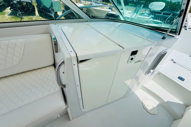 Slide: The Image of 2006 Glacier Bay 2670 Isle Runner boat interior with white seating and storage compartment. - 15