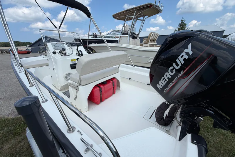 Slide: The Image of 2018 Boston Whaler 150 Montauk boat with Mercury engine, docked outdoors. - 6
