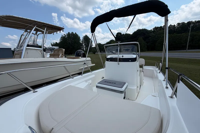 Slide: The Image of 2018 Boston Whaler 150 Montauk boat with canopy, parked outdoors under a cloudy sky. - 2