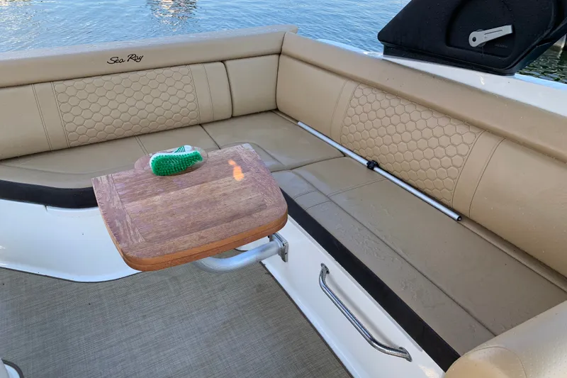 Slide: The Image of 2022 Sea Ray SDX 270 boat interior with beige seating and wooden table. - 19