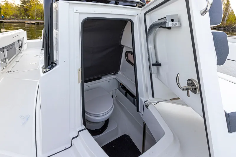 Slide: The Image of The 2027 Blackfin 252 CC features a compact onboard toilet with white interior and stainless steel fixtures. - 15