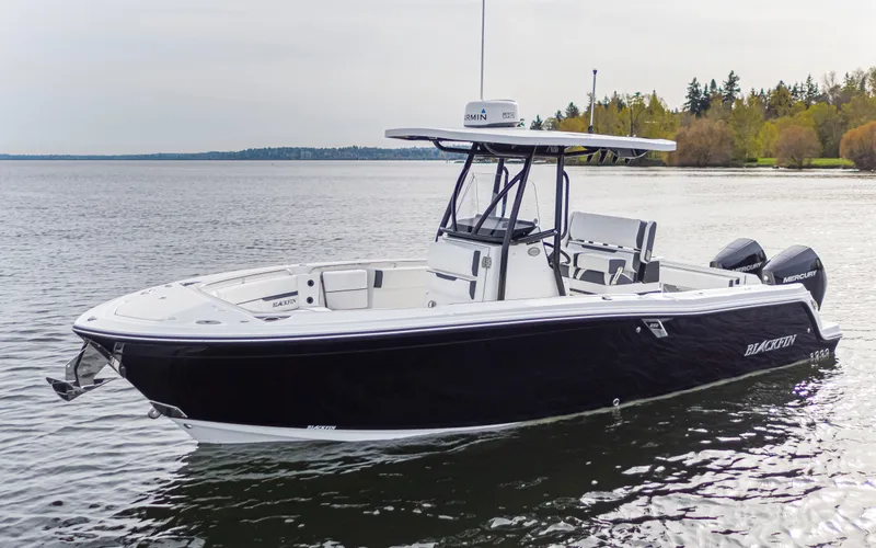 Slide: The Image of A sleek, modern boat with a black hull and white deck on calm water. - 1