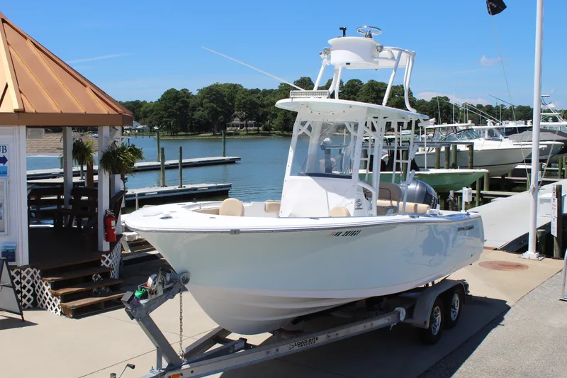 The Image of A white Sportsman Open 232 Center Console boat from 2019 is on a trailer at the dock. - 3