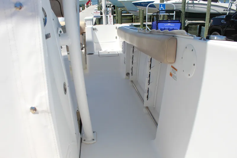 Slide: The Image of The image shows the deck of a 2019 Sportsman Open 232 Center Console boat. It features a white surface with beige upholstery and is docked. - 23
