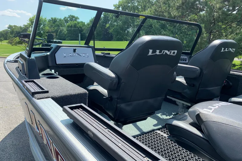 Slide: The Image of 2025 Lund 2075 Impact XS boat interior with black seats and console, outdoors. - 18