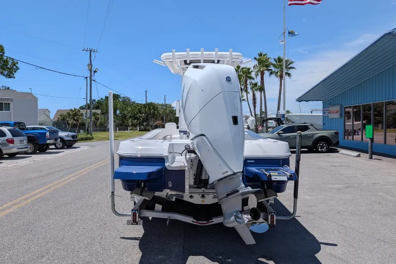 Slide: The Image of 2027 Caymas 26 HB boat with powerful outboard motor, parked on a sunny street. - 2
