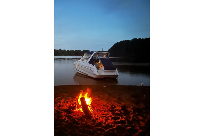 Slide: The Image of 2002 Wellcraft 2600 Martinique boat by a campfire on a serene lake at dusk. - 1