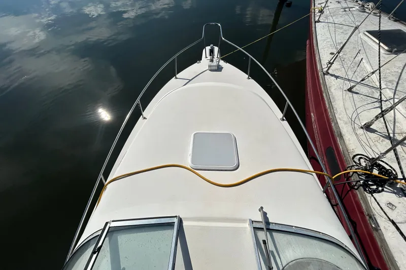 Slide: The Image of 2002 Wellcraft 2600 Martinique boat deck, docked beside another vessel, reflecting sunlight on water. - 11