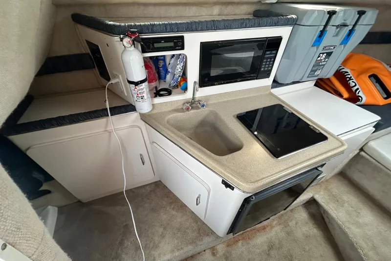 Slide: The Image of Compact kitchen area in a 2002 Wellcraft 2600 Martinique boat with sink, microwave, and storage. - 8