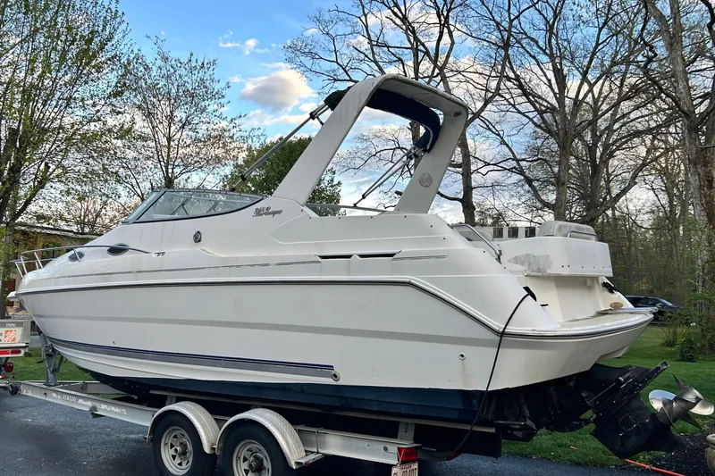 Slide: The Image of 2002 Wellcraft 2600 Martinique boat on trailer, surrounded by trees and blue sky. - 16
