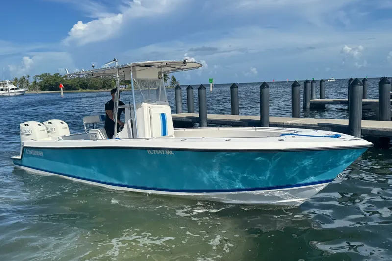 Slide: The Image of 2003 Contender 25 Open boat with dual Suzuki engines docked by the water. - 24