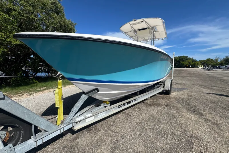 Slide: The Image of 2003 Contender 25 Open boat on trailer, parked outdoors under clear blue sky. - 2